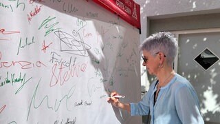 Marlene Kaplik unterschreibt auf einer Unterschriften-Wand für den Verbleib des Audi-Werks Neckarsulm