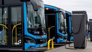 E-Busse der DB Regio Bus Mitte GmbH stehen auf einem Parkplatz mit Ladesäule und warten auf ihren Einsatz: Am 14.12. stellt Speyer im Stadtverkehr komplett auf Elektro-Busse um