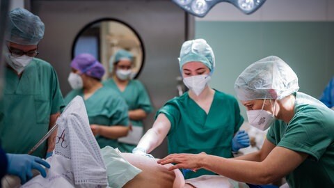Medizinsches Personal bei einem Kaiserschnitt am OP-Tisch