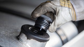 Ein LKW-Fahrer hält den Tankverschluss in der Hand. 