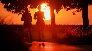 Zwei Frauen joggen, während hinter ihnen die rote Sonne aufgeht. Am Mittwoch erwartet der Deutsche Wetterdienst den Höhepunkt der Hitzewelle in Baden-Württemberg. Die Temperaturen erreichen bis zu 40 Grad.