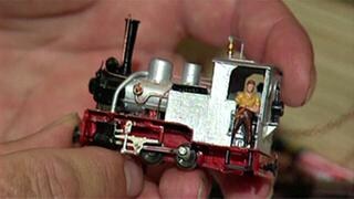 Eine Hand hält eine Modelleisenbahn