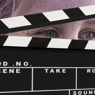 Eine Frau schaut durch eine Filmklappe