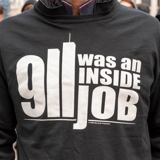 Eine Person trägt ein T-Shirt mit einer Verschwörungstheorie.