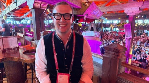 Greenox-Startup Gründer Maximilian Seifert sitzt beim Gründerwasen im Festzelt "Almhütte Royal".