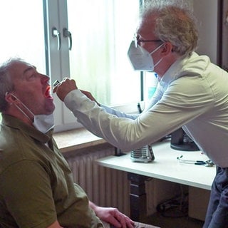 Arzt untersucht Rachen eines Patienten