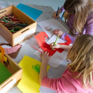 Grundschülerinnen sind in einem Kinderhort mit Bastelarbeiten beschäftigt. Nach den Sommerferien haben alle Erstklässler in RLP einen Anspruch auf Ganztagsbetreuung.