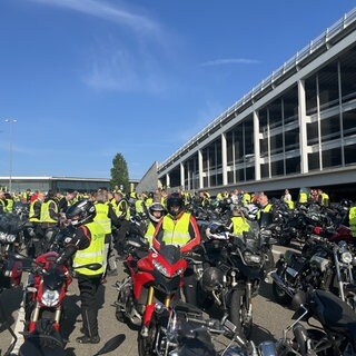 Mehrere Motorradfahrerinnen und -fahrer warten auf den Start des Korsos.