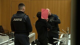 Ein Angeklagter wird in einen Gerichtssaal geführt