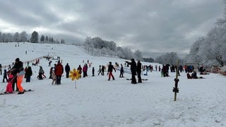 Dunkle Wolken über Wintersportlern am Felderhaldelift in Isny. Aber es liegt Schnee.