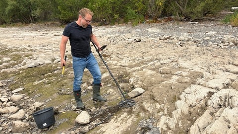Schatzsucher Christian Ganser ist bei Niedrigwasser mit seinem Metalldetektor am Rheinufer unterwegs