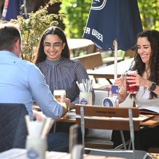 Personen genießen ein Getränk im Außenbereich eines Restaurants. 