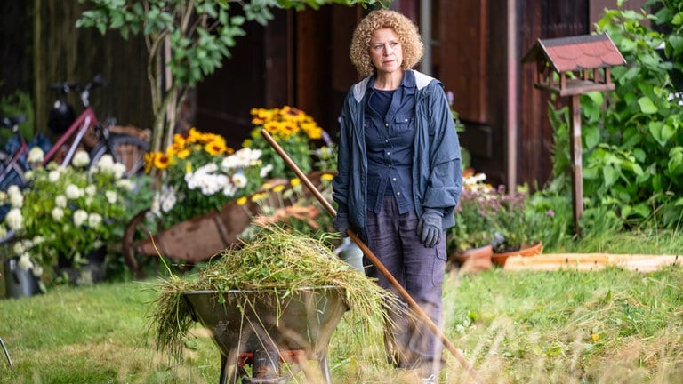 Bea (Christiane Brammer) steht hinter einer mit Gras beladenen Schubkarre bei Franziskas Waldhaus