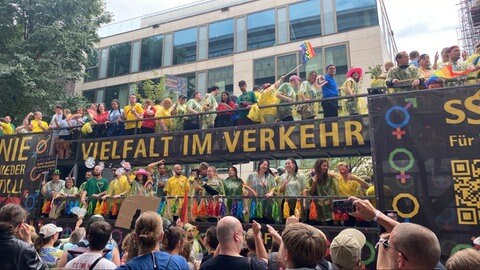 Menschen fahren auf einem Wagen bei der Parade des CSD Stuttgart 2025 mit.