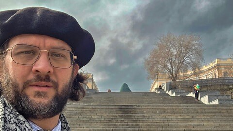 Johannes Kretschmann an der Potemkinschen Treppe in Odessa, im Hintergrund Rauch nach einem russichen Drohnenangriff