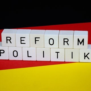 Auf Würfeln auf einer Deutschlandfahne steht "Reformpolitik".