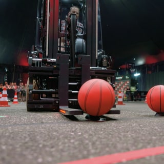 Ein Stapler trasportiert geschickt einen Basketball.