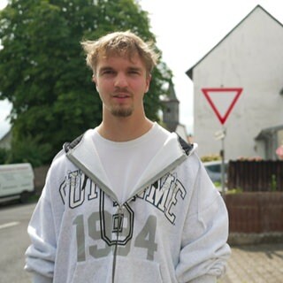 Mann im grauen Pullover steht auf der Straße