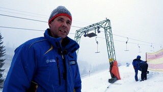 Matthias Schneider steht im Winter vor einem Skilift in Todtnauberg. Er trägt eine blaue Winterjacke und eine Mütze. Es liegt Schnee.
