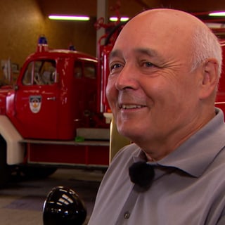 Mann steht vor Oldtimer-Feuerwehrauto