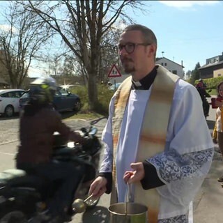 Ein Pfarrer segnet Motorräder bei der Vorbeifahrt