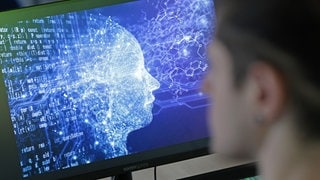 Ein Mensch und daneben ein PC mit Künstlicher Intelligenz.