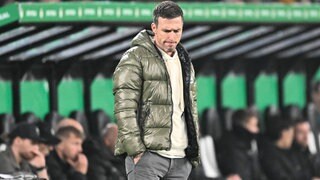 KSC-Trainer Christian Eichner schaut während des DFB-Pokal-Spiel bei Borussia Mönchengladbach nachdenklich zu Boden.