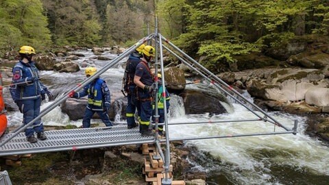 Männer bauen eine Brücke, die über die Murg führen soll. 