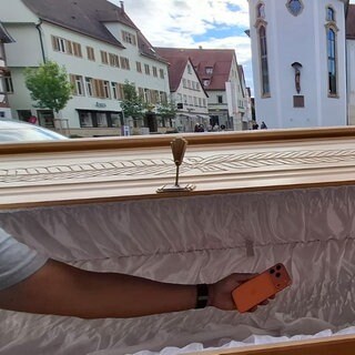 Ein Handy wird in einen Sarg gelegt. Das ist Teil einer Ausstellung in der Johanniskirche in Schwäbisch Gmünd. Es geht dabei auch um Digital Detox.