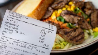 Eine Rechnung neben einem vollen Teller in einem Restaurant. (Symbolbild).
