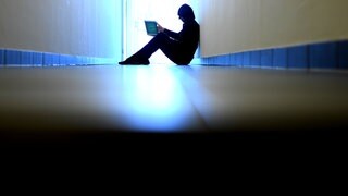 Mann sitzt mit Laptop auf dem Boden