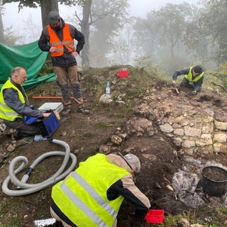 Im nebligen Wald werden Überreste einer Mauer freigelegt. Studierende und Mitarbeitende der Uni Tübingen beginnen mit den Ausgrabungen an der Burg Hohengenkingen.