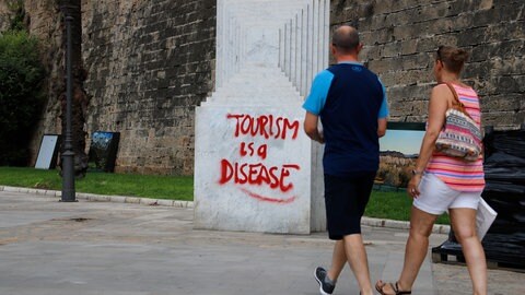 Graffiti mit einer Botschaft gegen den Tourismus auf einer Skulptur im Zentrum von Palma auf Mallorca.