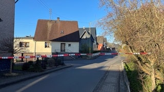 Ein rot-weißes Polizeiband sperrt den Tatort in Weitefeld im Westerwald ab. Laut dem Bürgermeister sind alle Sportveranstaltungen in dem Ort abgesagt.