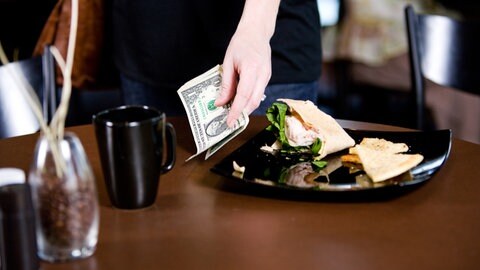 Frau gibt im Restaurant Trinkgeld