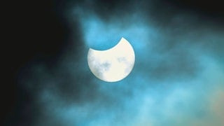 Partielle Sonnenfinsternis, der Himmel ist leicht bedeckt und die Sonne wird vom Mond oben etwas angeknabbert