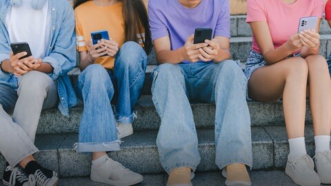 Kinder sitzen mit Mobiltelefonen auf einer Treppe