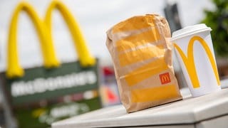 Eine McDonald's To-Go-Tüte und ein To-Go-Becher stehen vor einer Tübinger McDonald's-Filiale. McDrive Kunden in Tübingen müssen keine Verpackungssteuer zahlen.