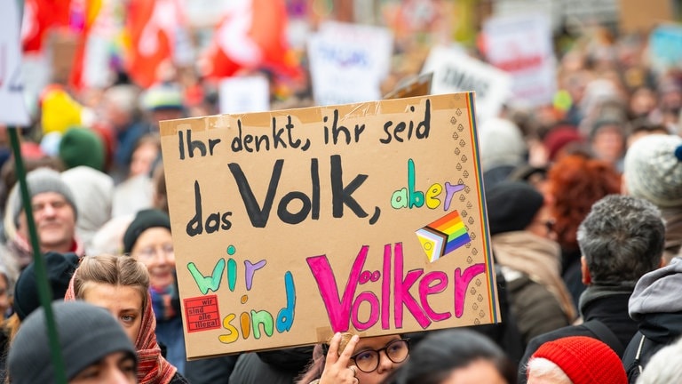 "Ihr denkt, ihr seid das Volk, aber wir sind Völker" steht im Februar 2024 auf einem Schild bei einer Demonstration gegen Rechtsextremismus und die AfD in der Innenstadt von Lübeck. 