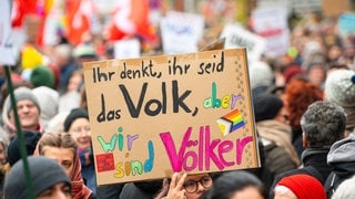 "Ihr denkt, ihr seid das Volk, aber wir sind Völker" steht im Februar 2024 auf einem Schild bei einer Demonstration gegen Rechtsextremismus und die AfD in der Innenstadt von Lübeck. 