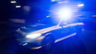 Ein Polizeifahrzeug fährt mit Blaulicht an einem Gebäude vorbei.