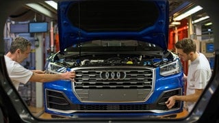 Fertigungsmechaniker bringen an einem Fließband im Audi-Werk die Front an einem Audi an.