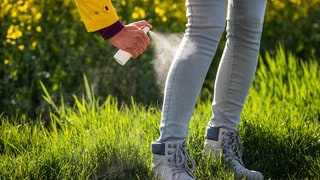 Frau sprüht ihre Hose mit Insektenschutz ein