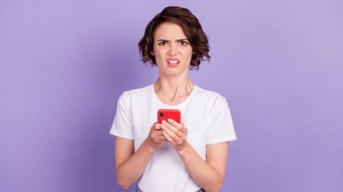 Eine Frau schaut irritiert von ihrem Smartphone auf