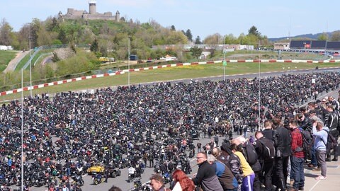 Viele tausend Menschen stehen auf der Rennstrecke Nürburgring. Im Hintergrund die Ruine der Nürburg