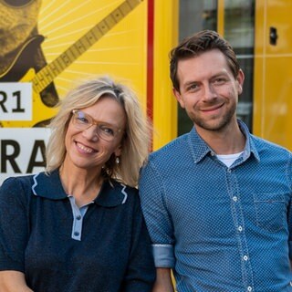 Die SWR1 Hitparaden Tour mit Stefanie Anhalt und Corvin Tondera-Klein vor einem gelben SWR-Fahrzeug macht Stopp in Aalen