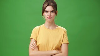 Eine unzufriedene Frau runzelt die Stirn und schürzt die Lippen