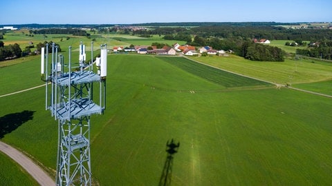 Ein Mobilfunkmast ragt aus der grünen Landschaft als Symbol für den schleppenden Ausbau von Mobilfunk in ländlichen Regionen. In Baden-Württemberg und Rheinland-Pfalz gibt es im Vergleich mit anderen Bundesländern die meisten Funklöcher.