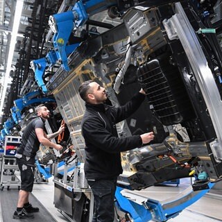 Mitarbeiter von Mercedes-Benz arbeiten in der Fertigung am Band. 