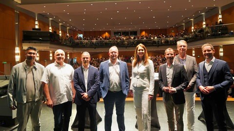 Die acht Kandidierenden der OB-Wahl in Weinheim auf der Bühne in der Stadthalle 